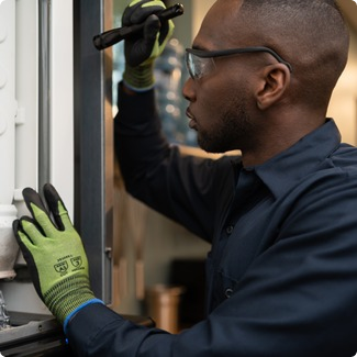 Service technician in work gloves holding a flashlight while inspecting commercial kitchen equipment
