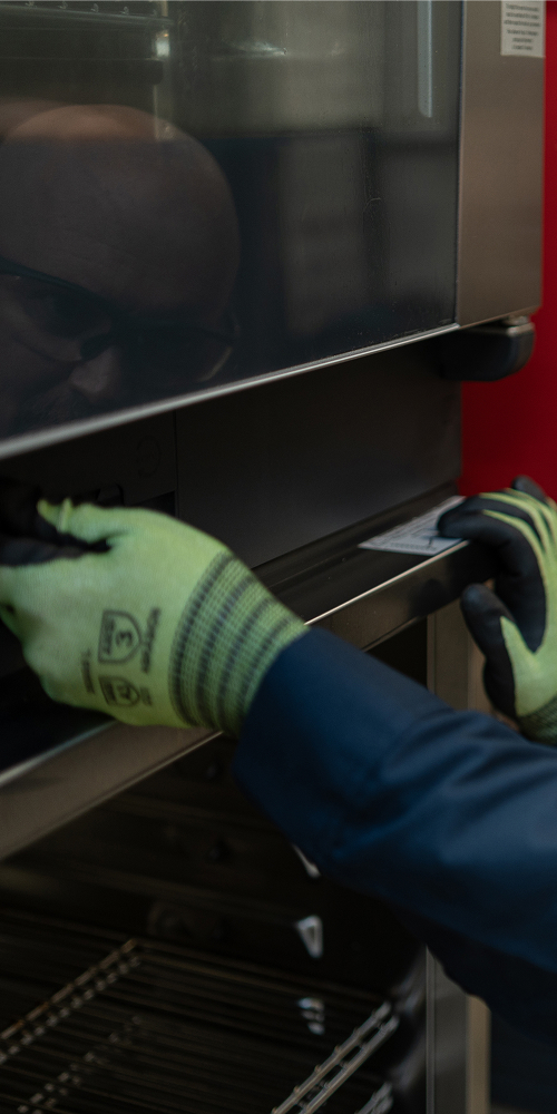 Service technician in safety glasses and work gloves servicing a commercial oven