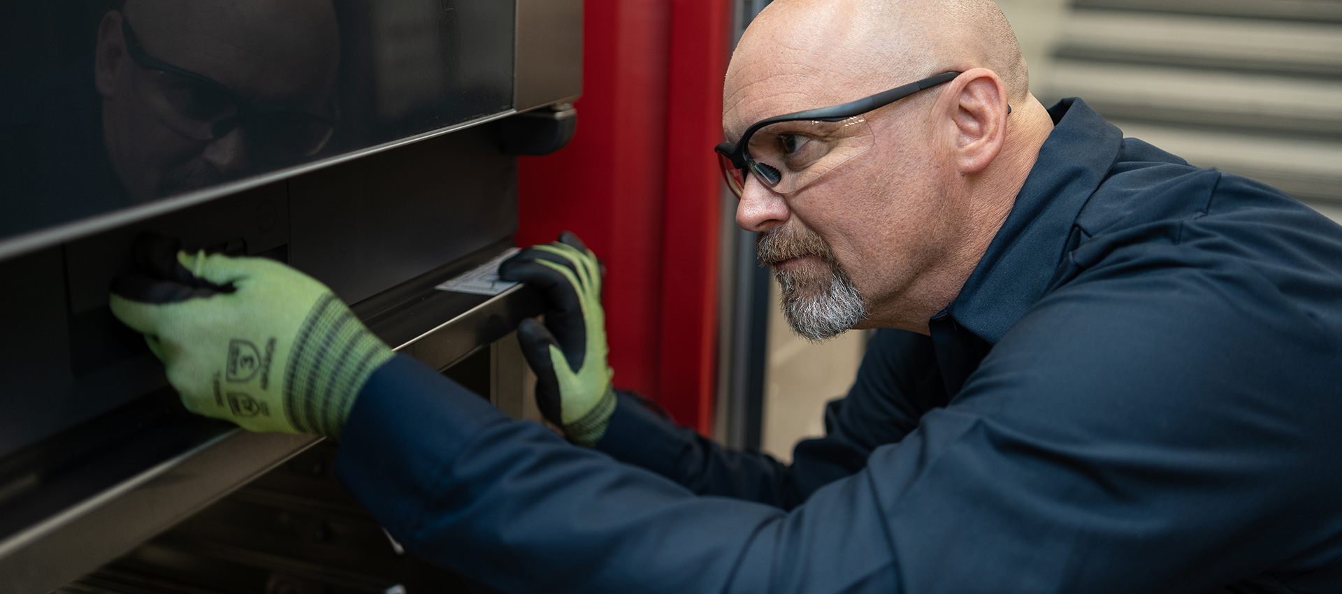 Service technician in safety glasses and work gloves servicing a commercial oven