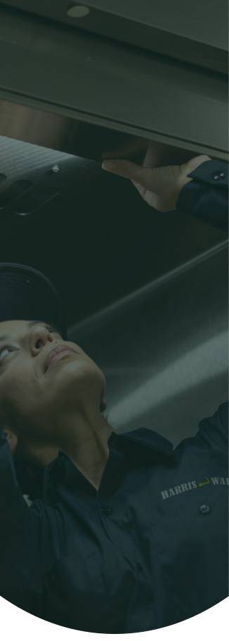 Service technician reaching up to work on a commercial kitchen exhaust hood